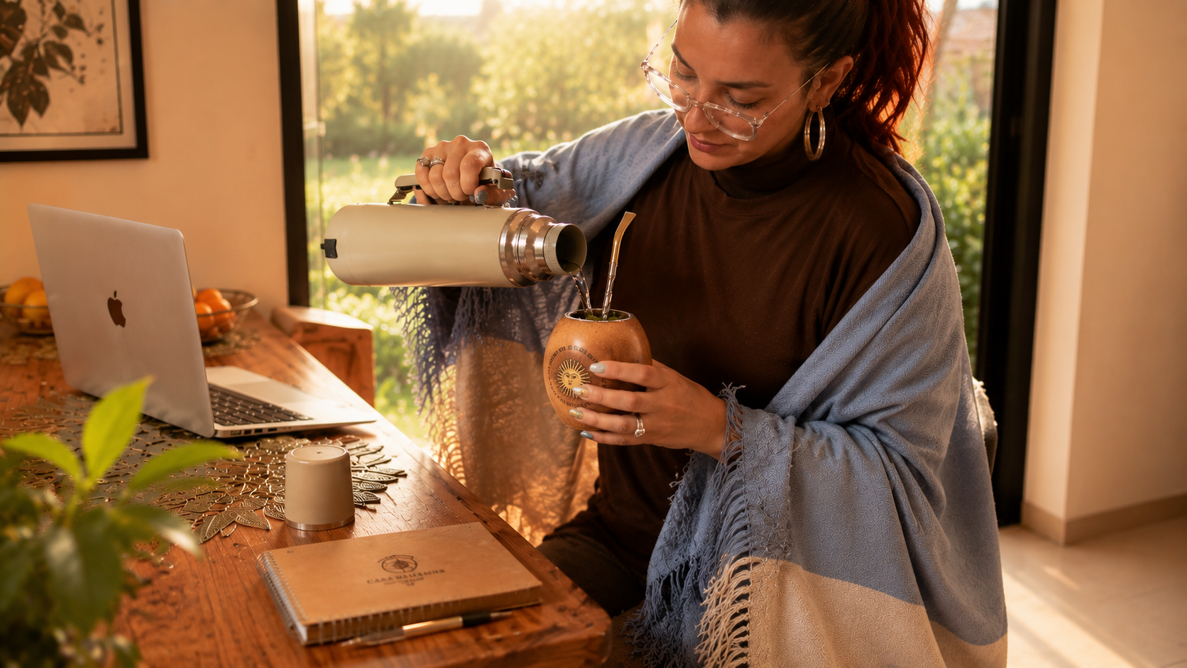 Mujer sirviendo mate con manta albiceleste en un ambiente cálido de Casa Mandarina